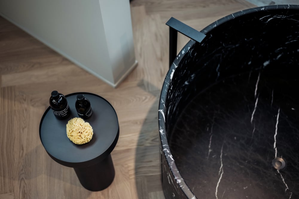 Top view of Anfora round black marble freestanding stone bathtub showing natural marble interior