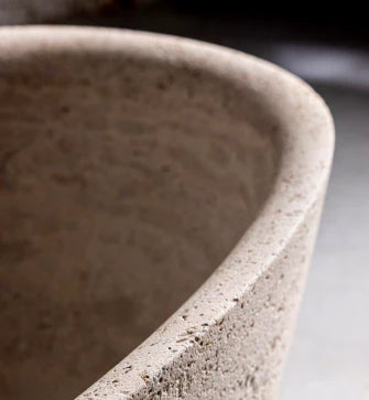 detail of anfora round travertine stone bathtub edge showing natural stone texture
