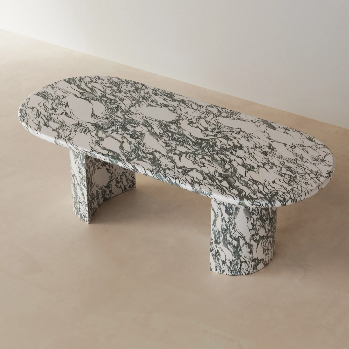 Anzio oval dining table in green marble viewed from angle with sculptural stone pedestal base