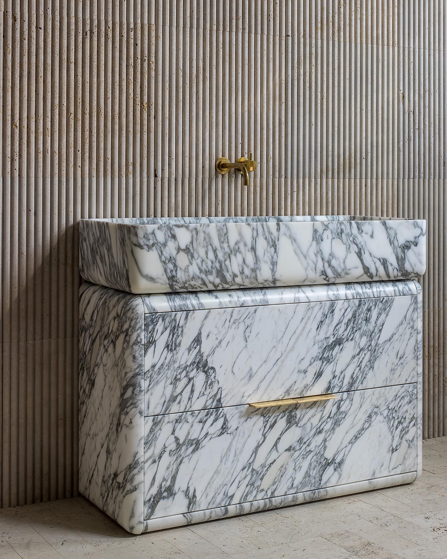 Modern marble bathroom vanity shown in angled view highlighting depth and sculptural form