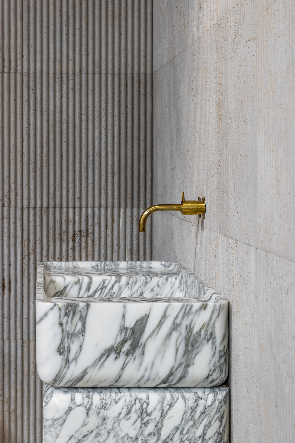 Marble vanity detail with brass faucet and natural stone texture in minimalist bathroom