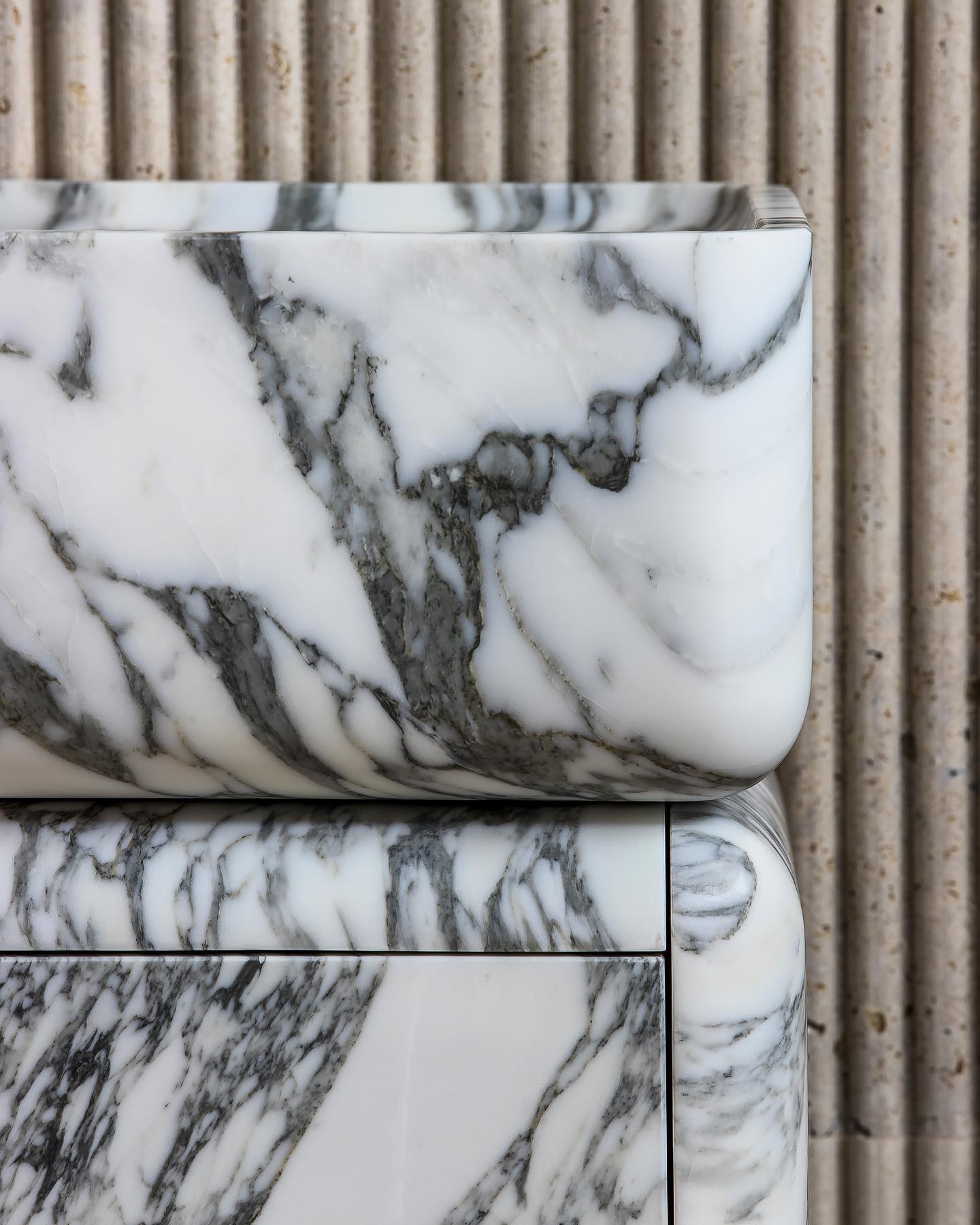 Close-up of marble vanity edge showing natural veining and rounded sculptural detail