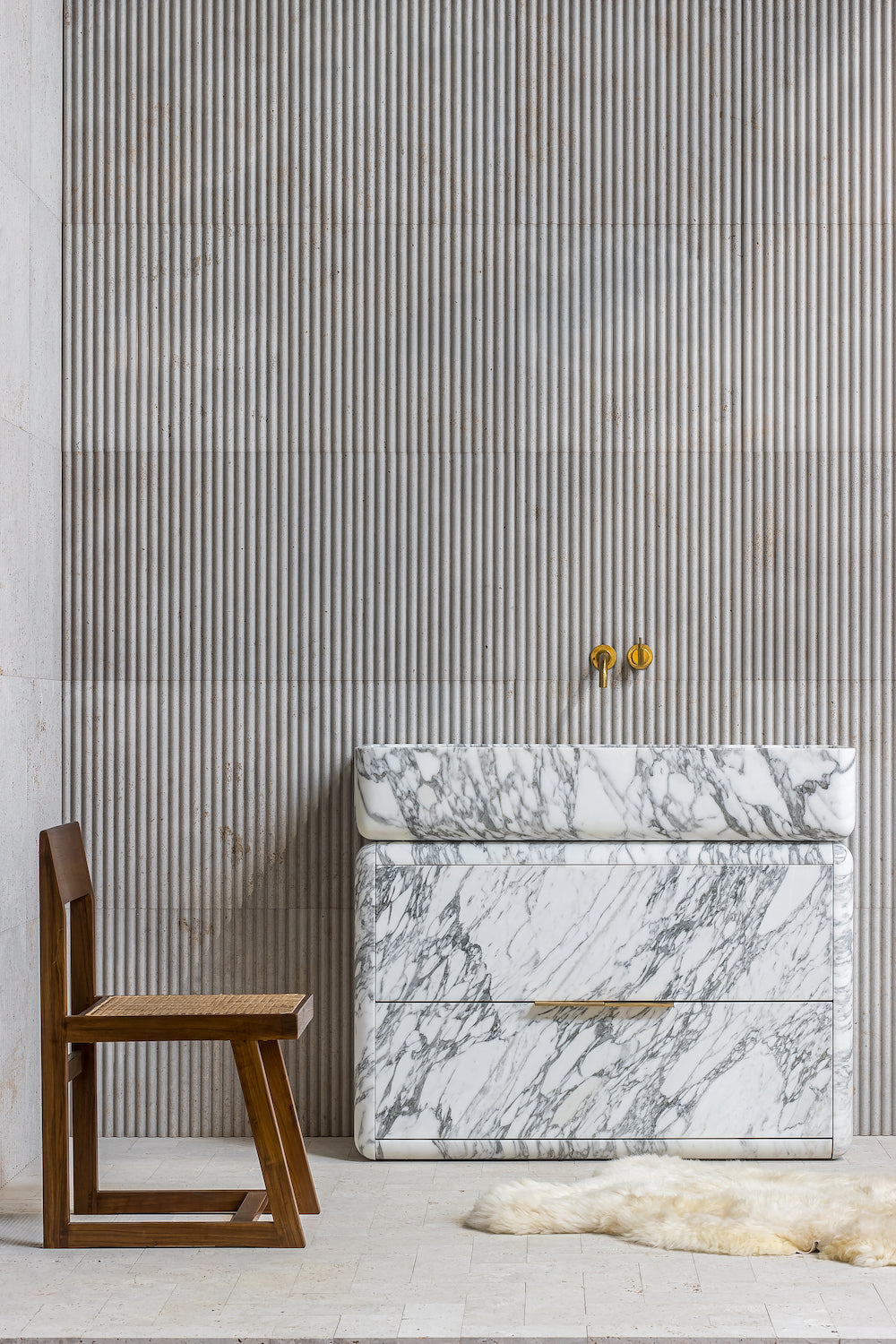 Minimalist marble bathroom vanity with brass faucet and natural light interior setting
