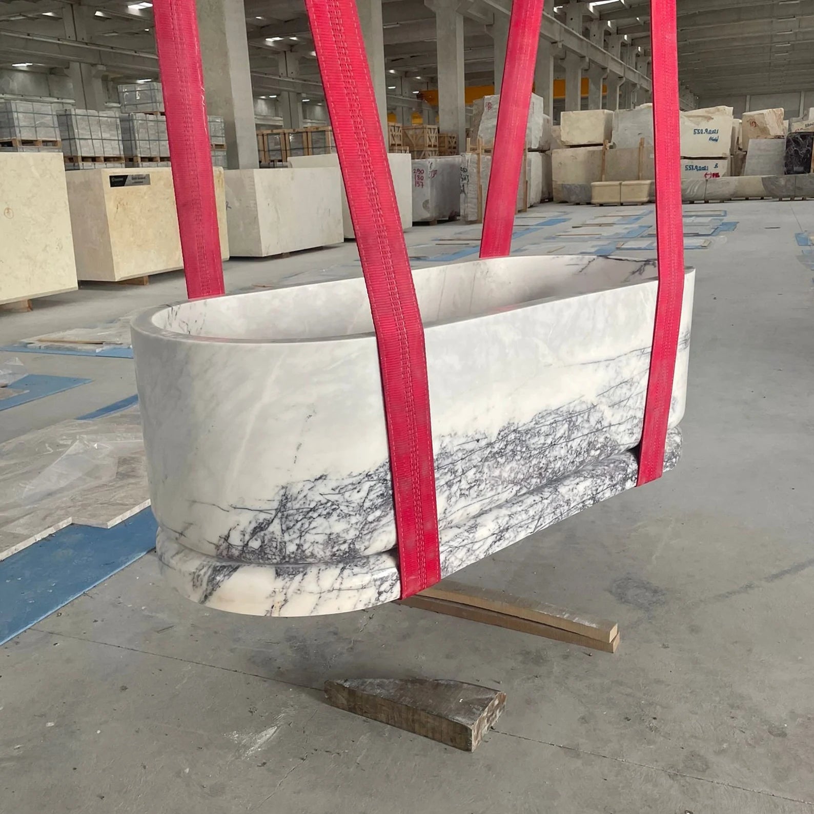 Calacatta marble freestanding bathtub being lifted in factory by Eden Stone Designs