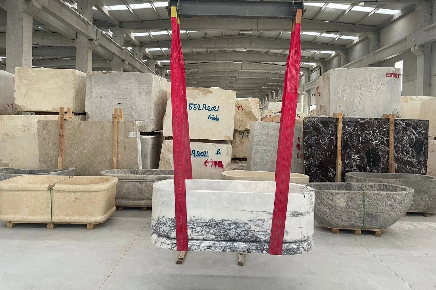 Calacatta marble freestanding bathtub being lifted in stone factory by Eden Stone Designs