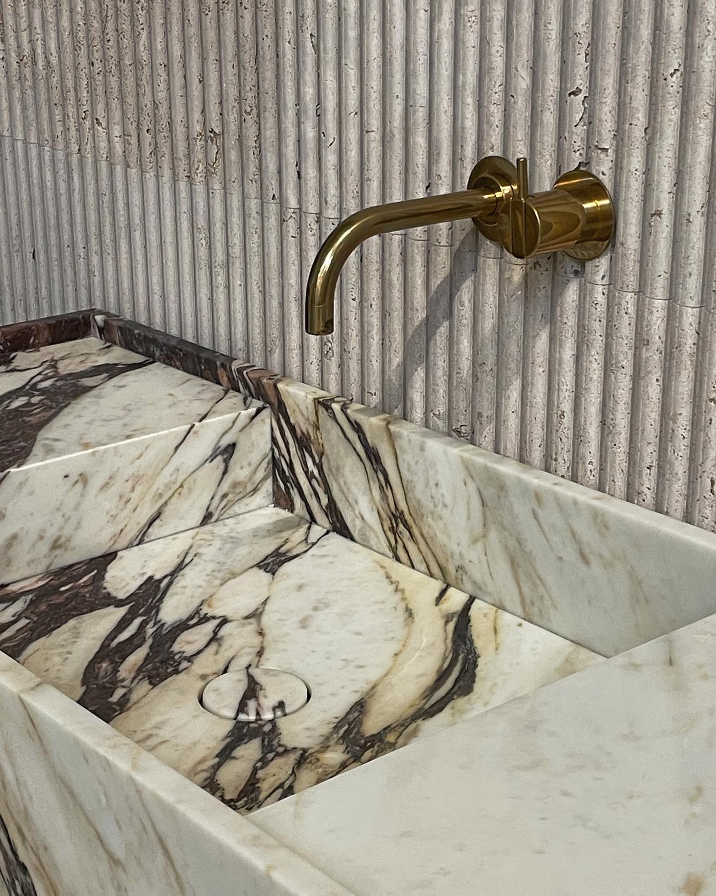 Florence marble vanity with integrated basin and wall mounted brass faucet in natural stone bathroom design