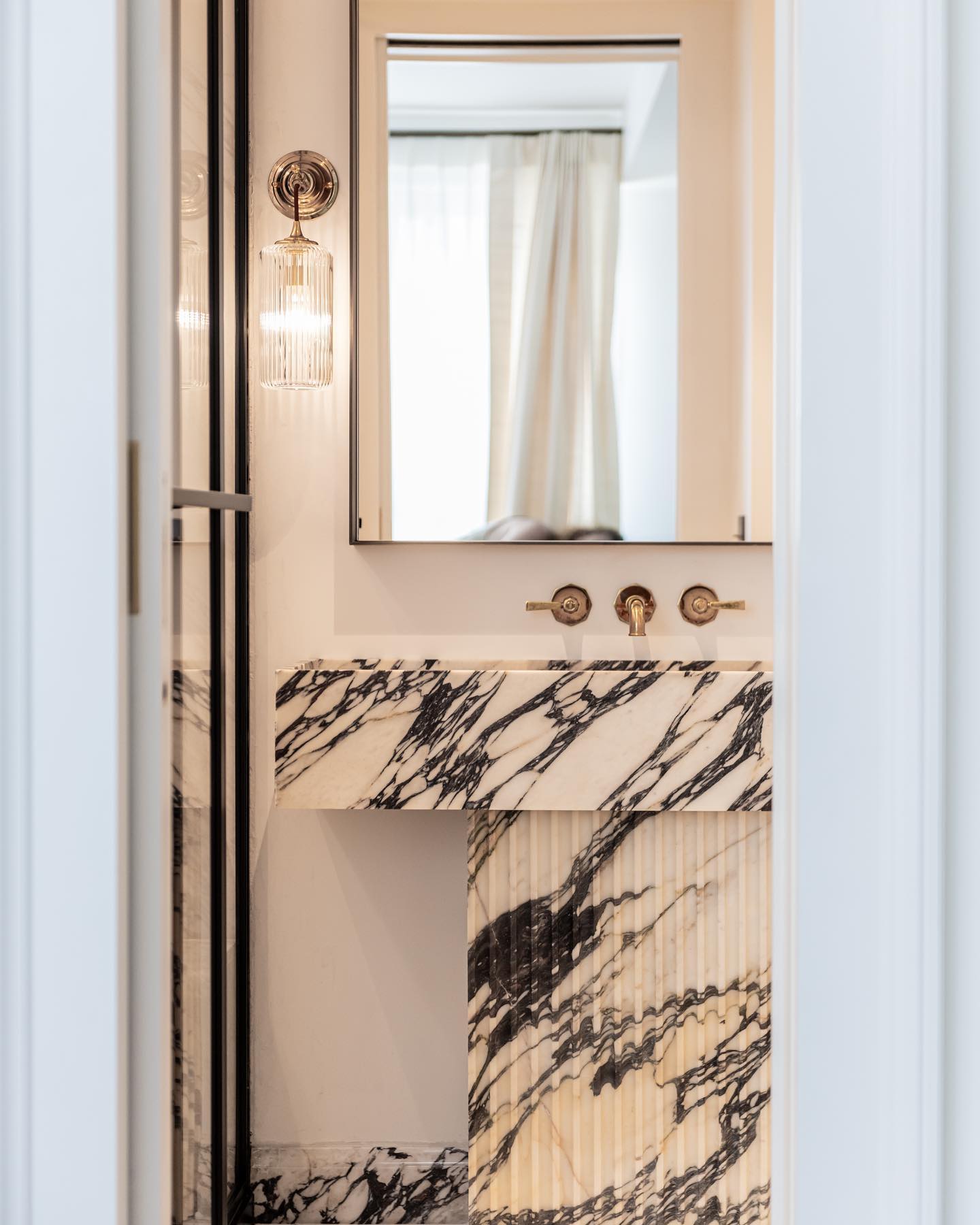 Florence marble vanity installed in bathroom with wall mounted faucet and mirror in luxury interior