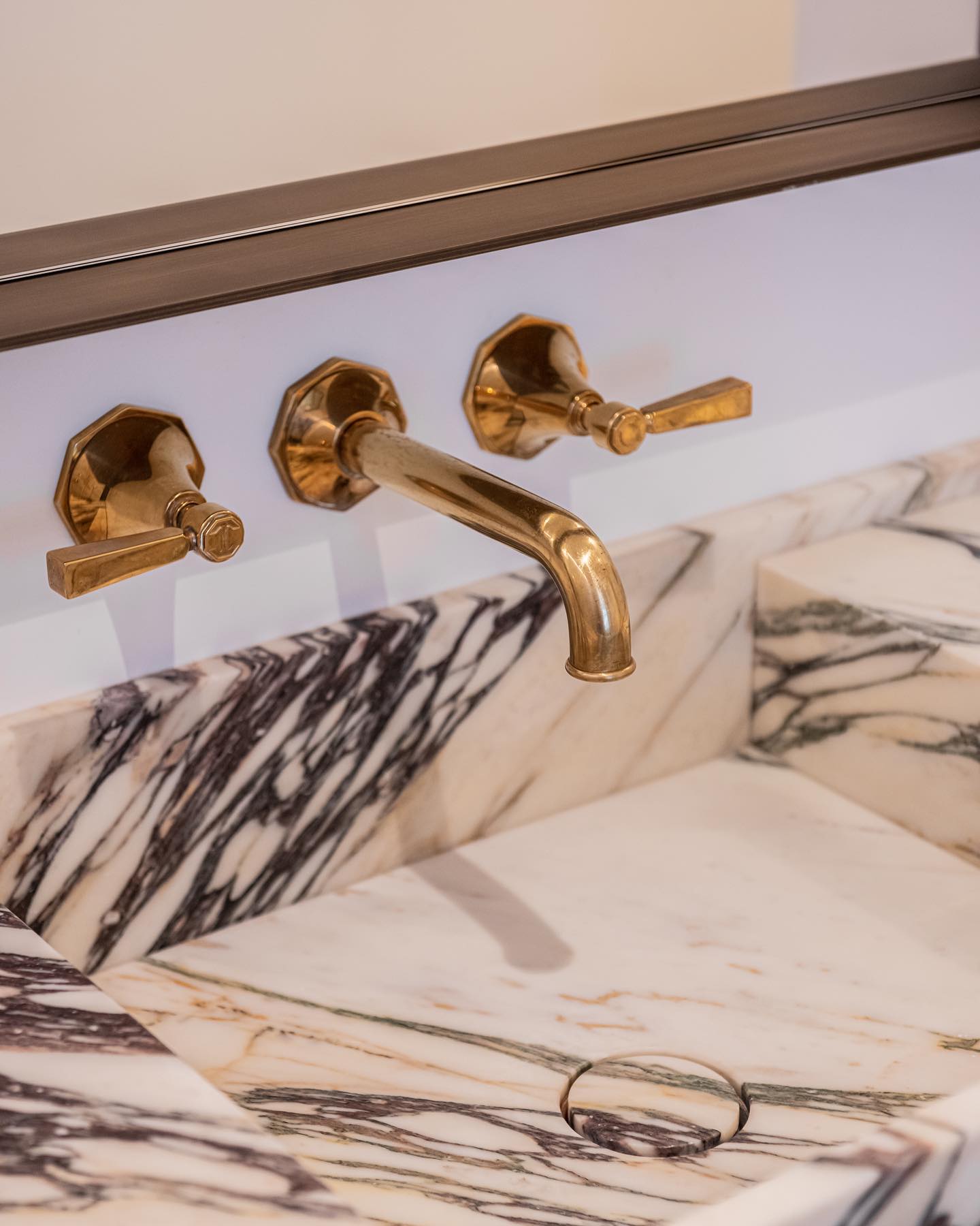 Florence marble vanity with integrated basin and wall mounted brass faucet detail in luxury bathroom