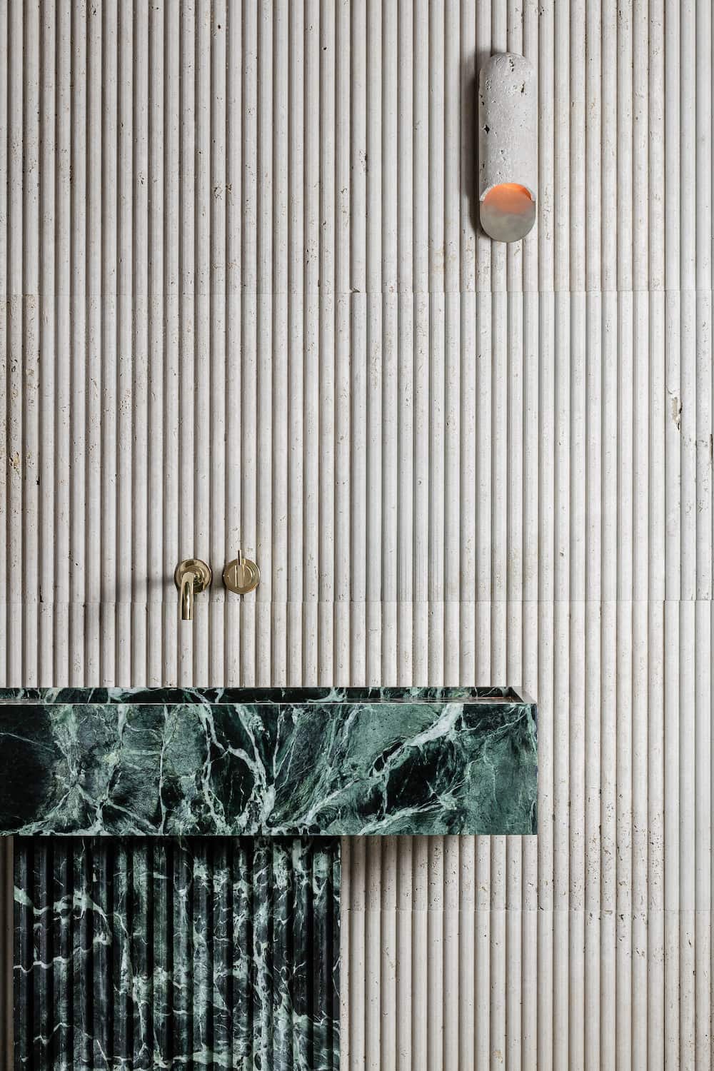 Florence marble vanity in green natural stone with fluted pedestal base in architectural bathroom setting