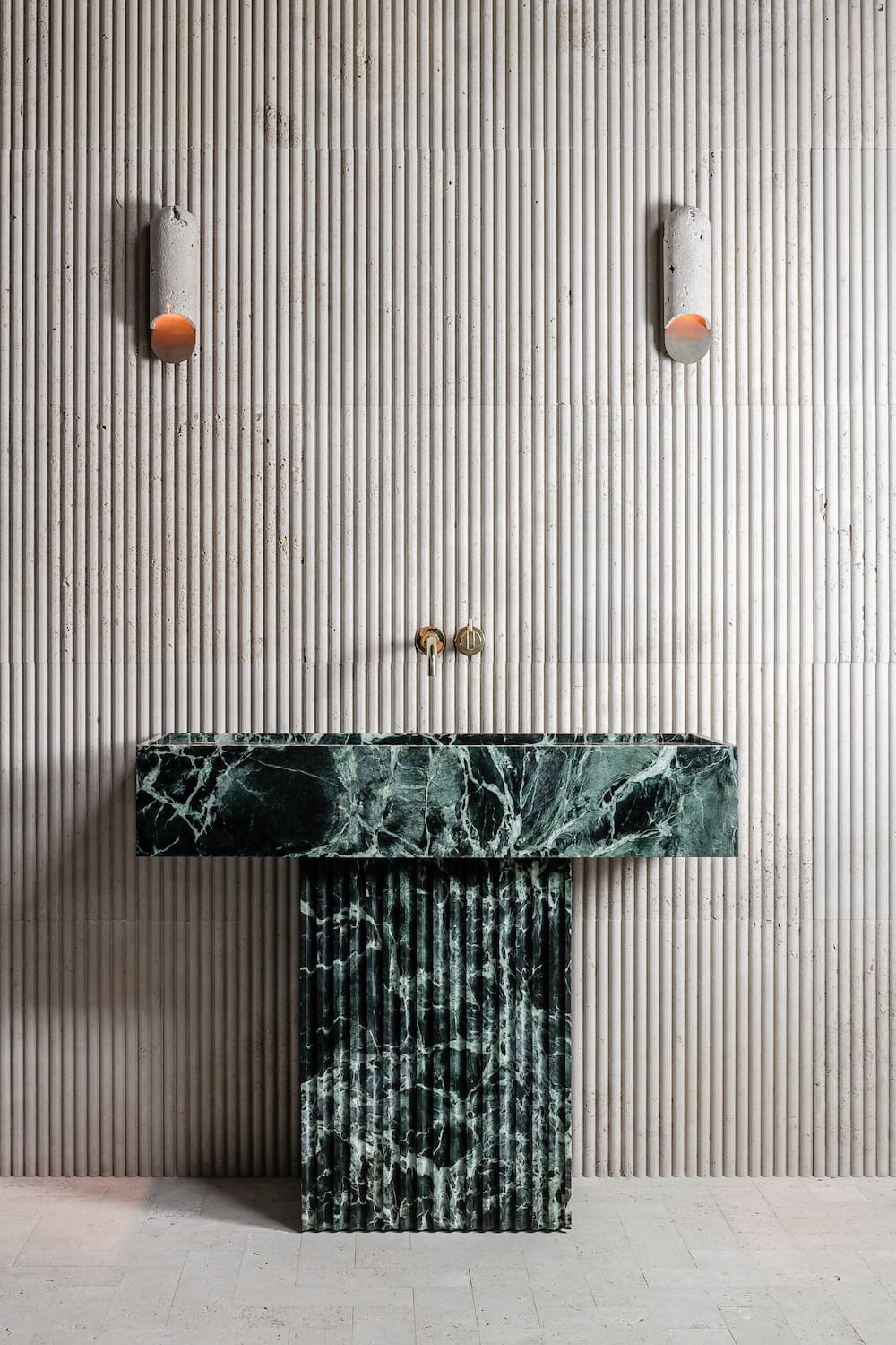 Florence marble vanity in green natural stone with fluted pedestal base and integrated sink in architectural bathroom