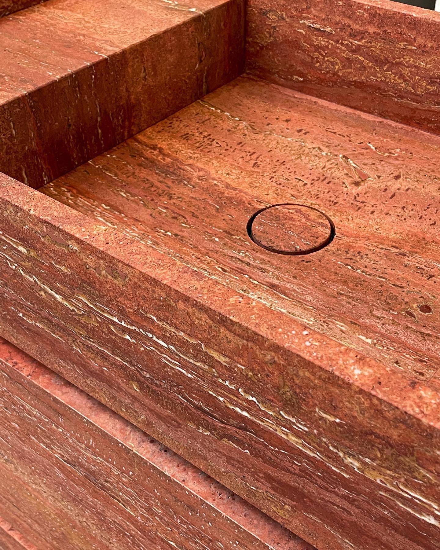 Top view detail of Genoa marble vanity basin showing red natural stone texture and integrated drain