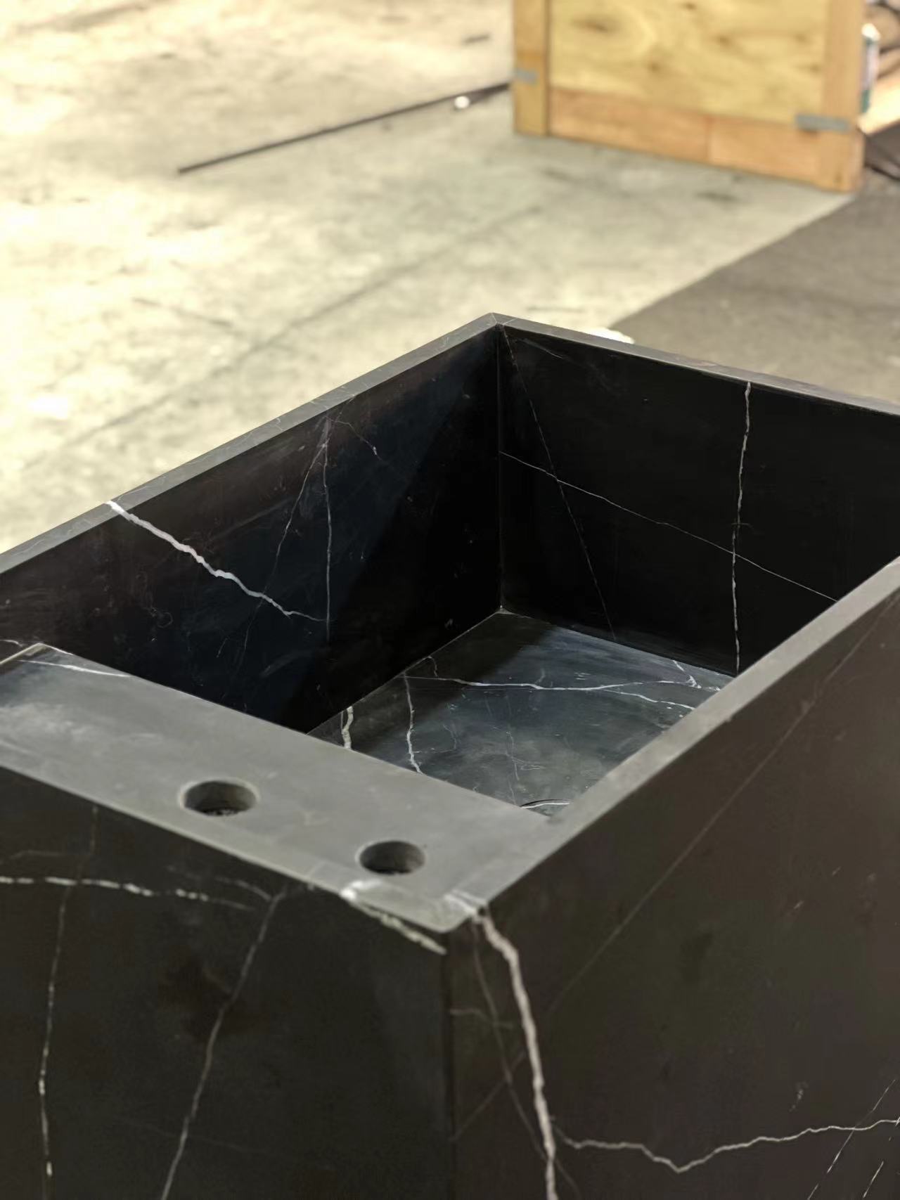 Top view detail of Genoa marble vanity in black natural stone showing carved basin and faucet openings in workshop