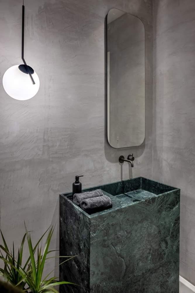 Genoa marble vanity in green natural stone installed in a modern bathroom with wall mounted faucet and mirror
