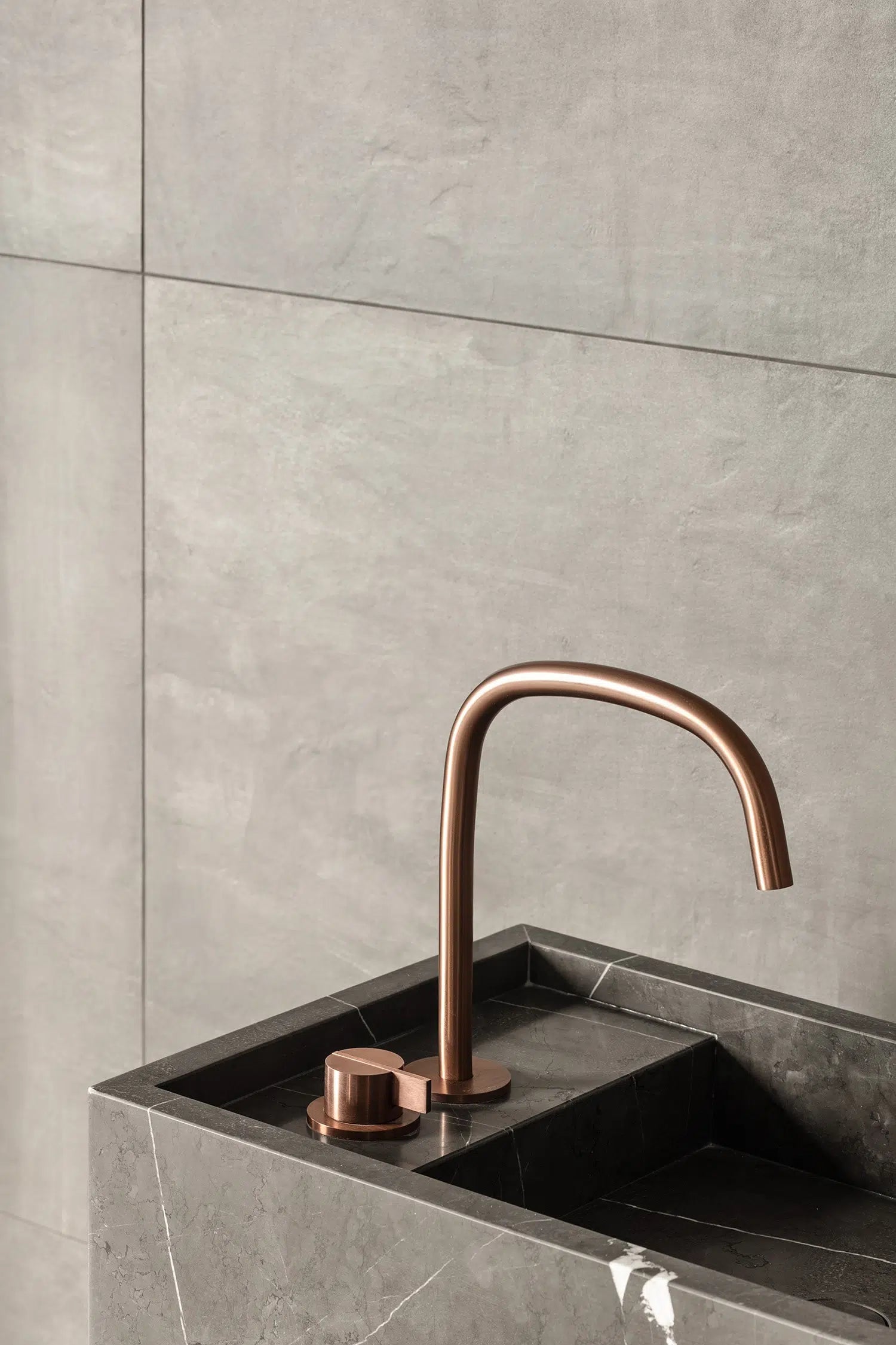 Close up of Genoa marble vanity in grey natural stone with integrated basin and brushed metal faucet detail