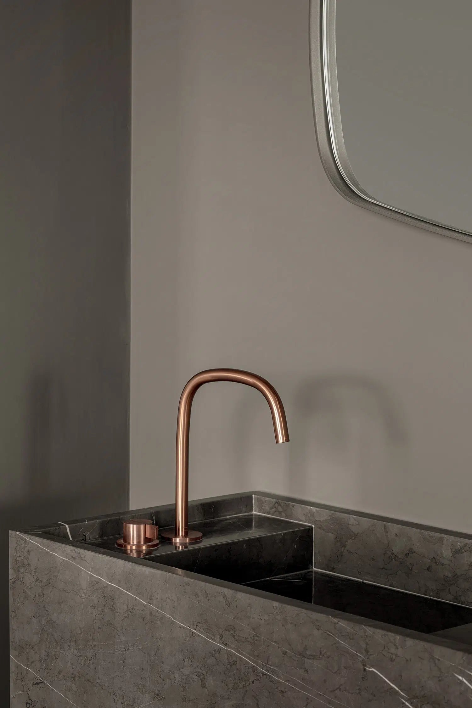 Close up of Genoa marble vanity in grey natural stone with integrated basin and brushed metal faucet