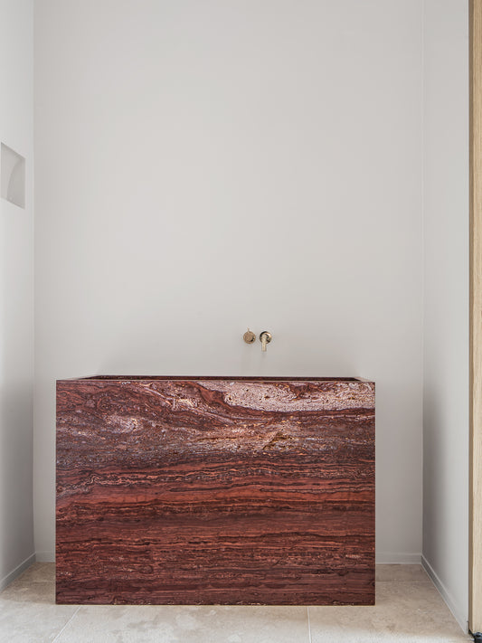 Genoa marble vanity in red natural stone with bold horizontal veining in a minimalist bathroom setting