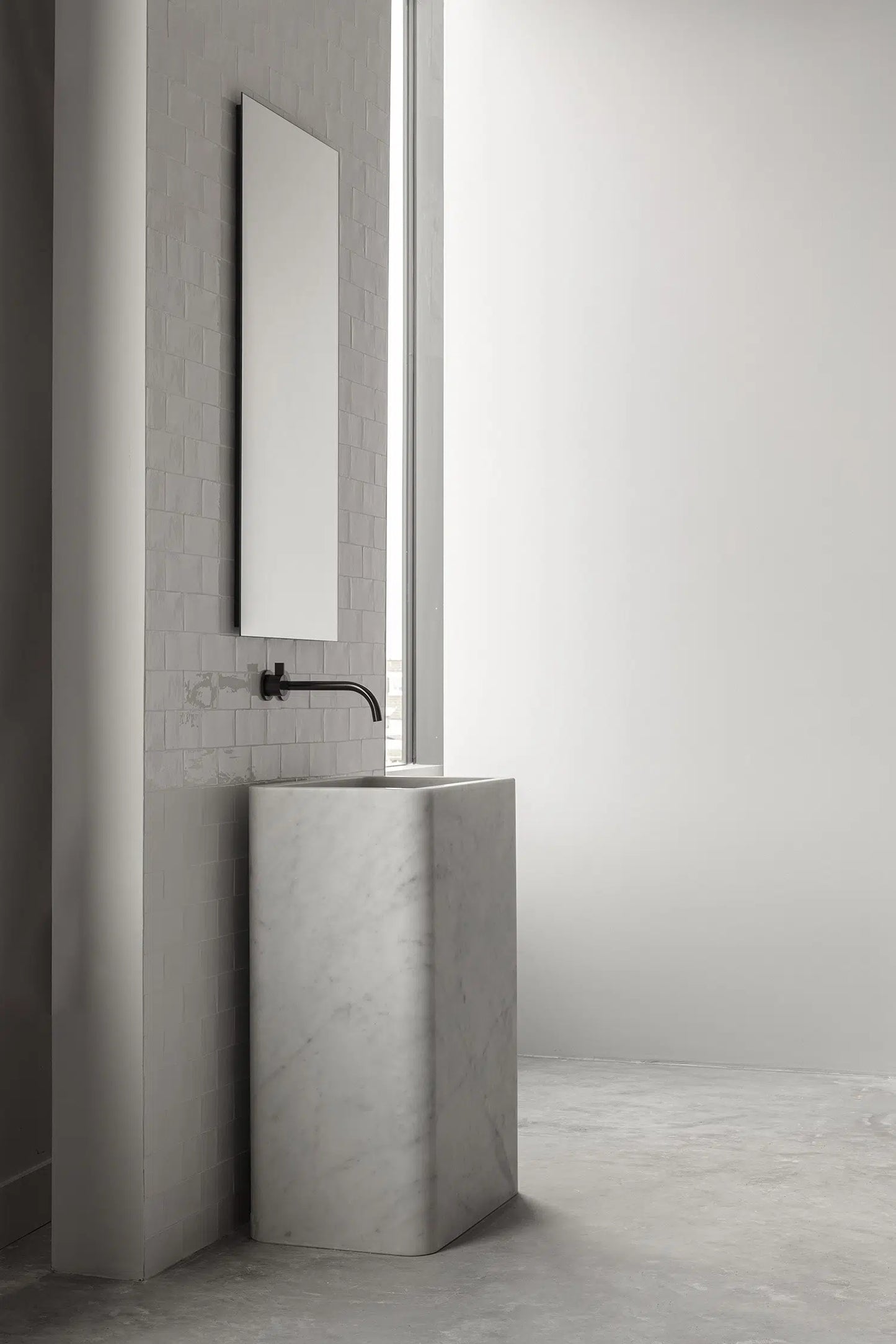 Genoa marble vanity in white natural stone installed in a minimalist bathroom with wall mounted faucet and mirror