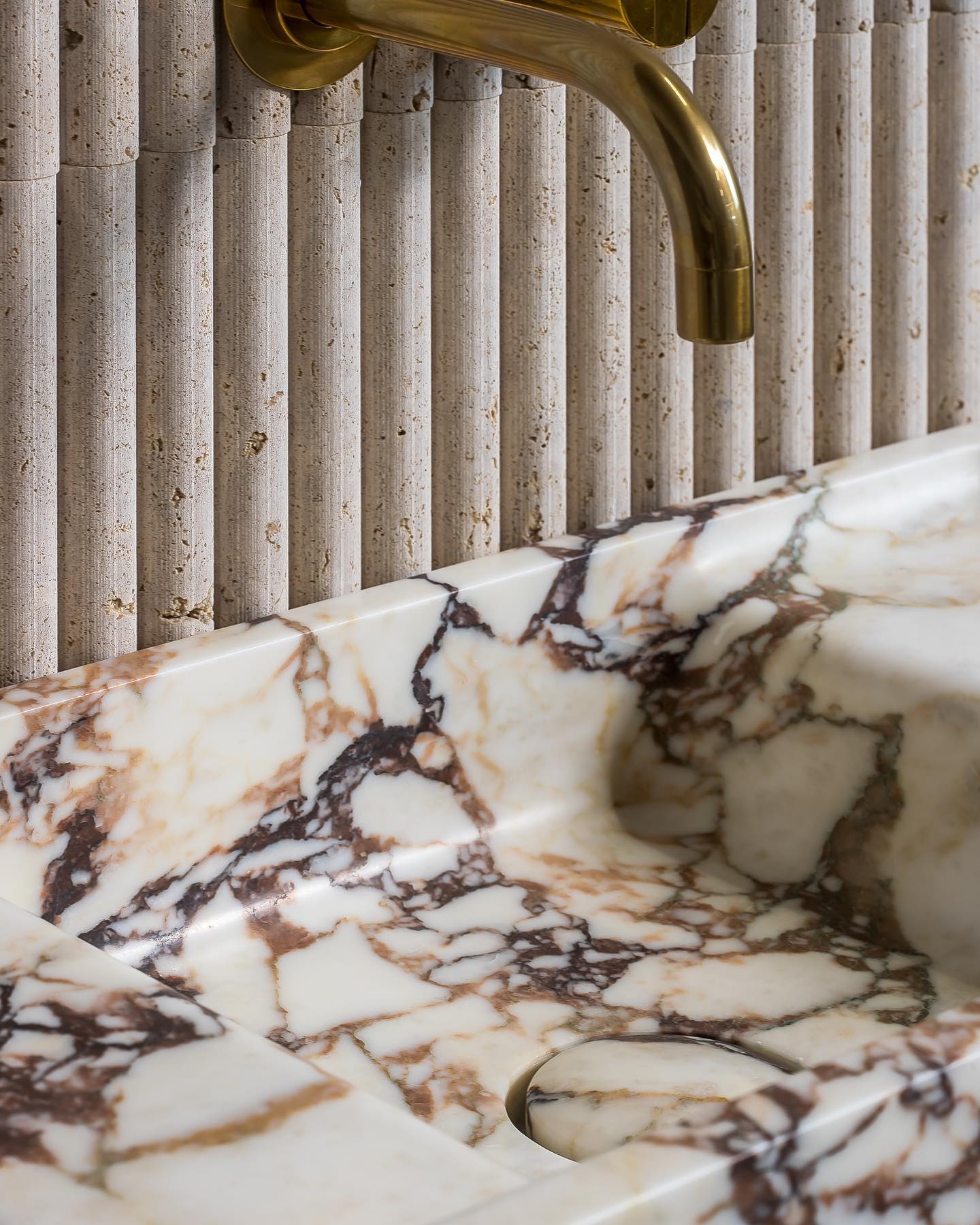 Calacatta Viola marble sink with brass faucet showing natural stone veining and texture