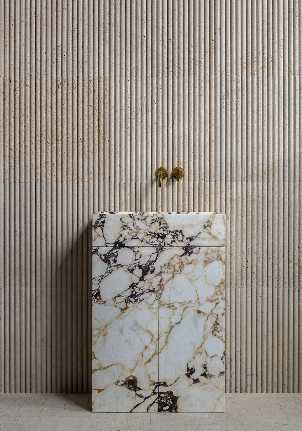 Marble bathroom vanity in Calacatta Viola with bold veining and fluted stone wall background