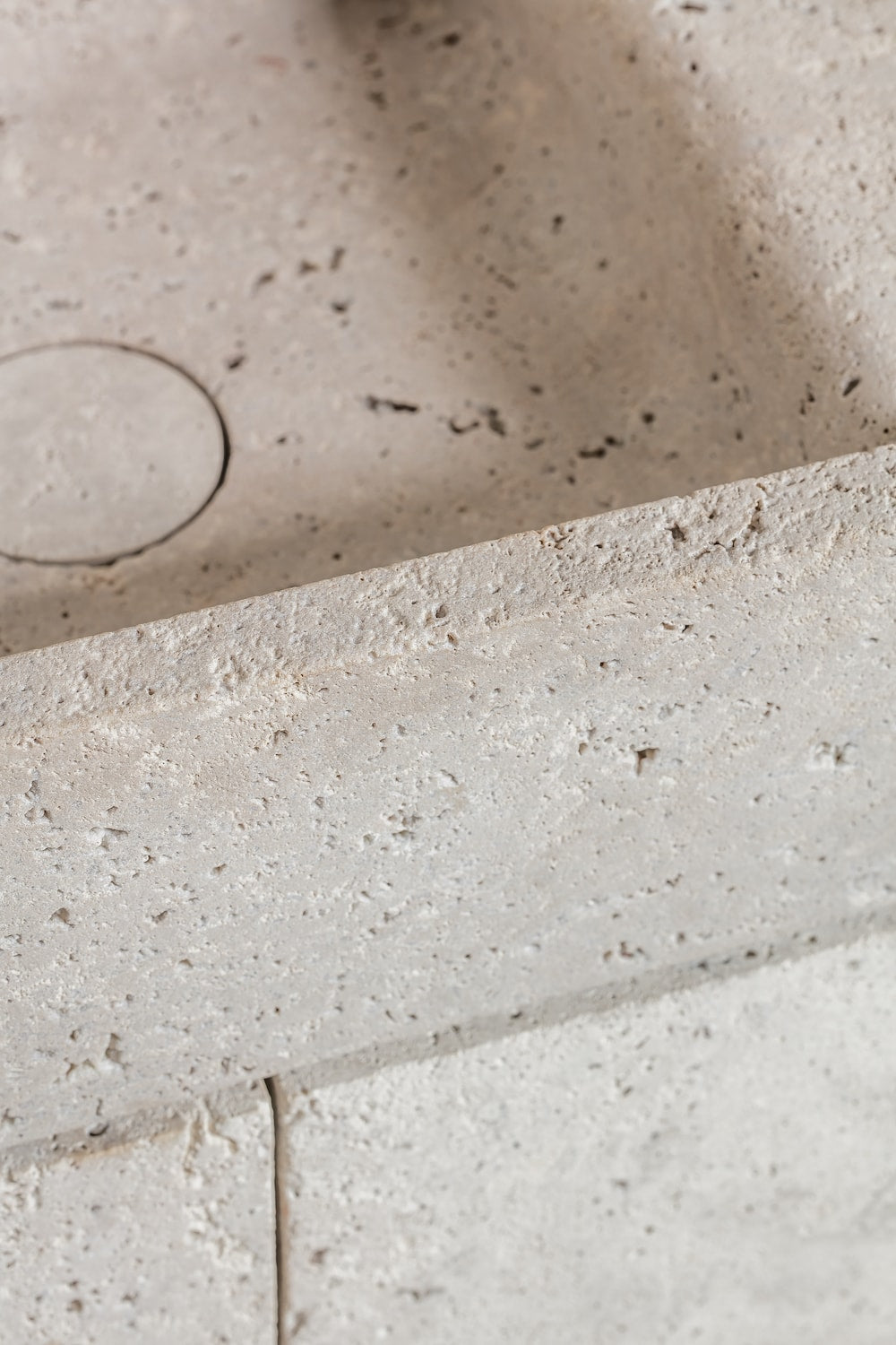 Close-up of natural stone vanity edge with textured surface and integrated basin detail