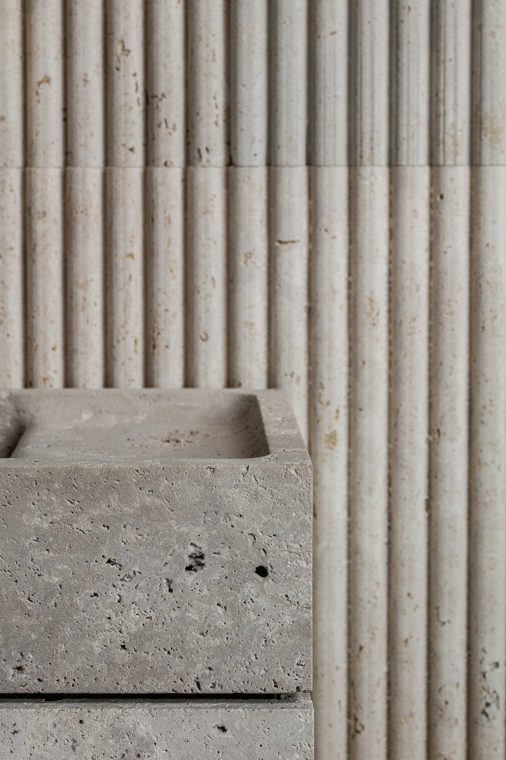 Minimalist stone vanity detail with fluted wall background and natural textured surface