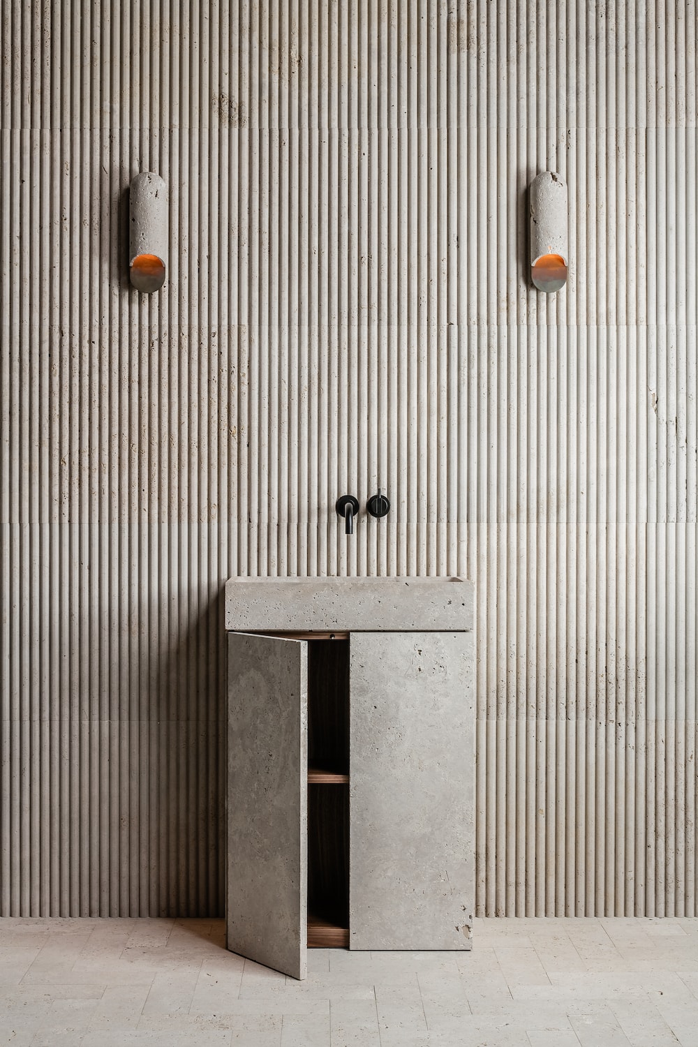 Stone bathroom vanity with open cabinet showing storage in minimalist architectural interior