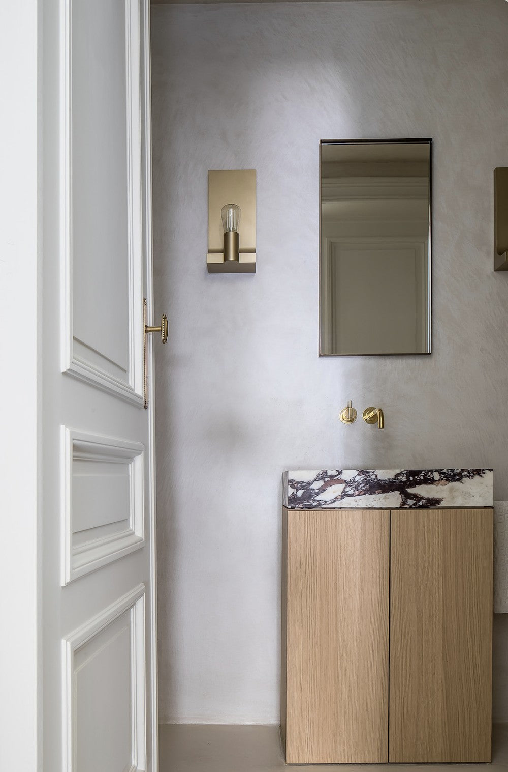 Wooden bathroom vanity with marble top in modern minimalist interior with brass fixtures