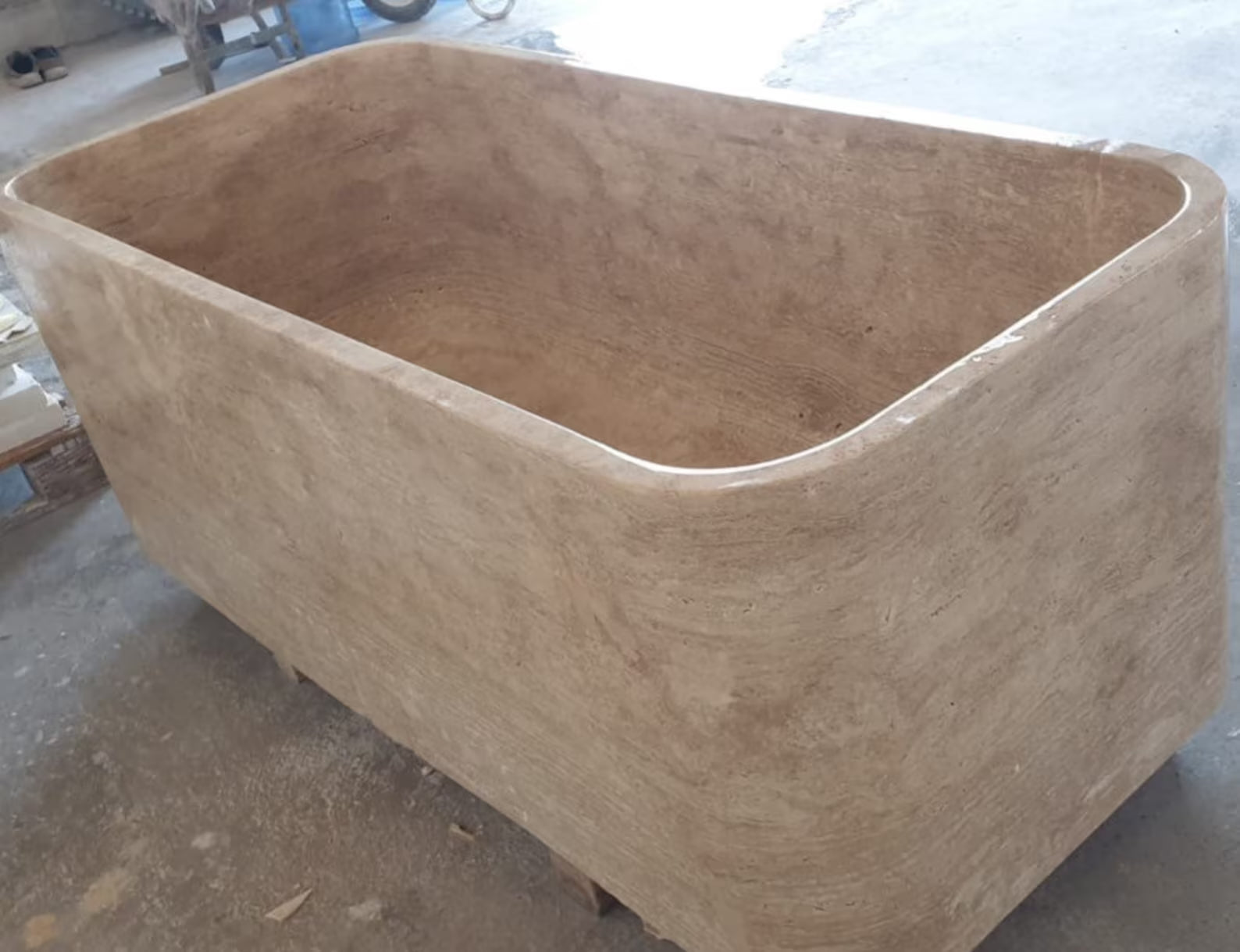 Mirlo travertine stone bathtub carved from solid natural stone showing sculptural freestanding design from angle