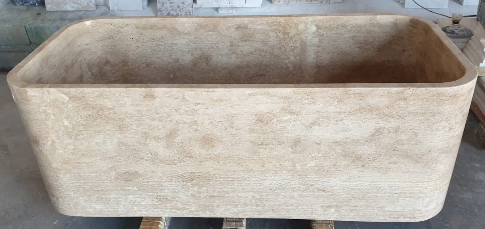 Mirlo travertine stone bathtub carved from a solid block of natural stone showing sculptural rectangular form