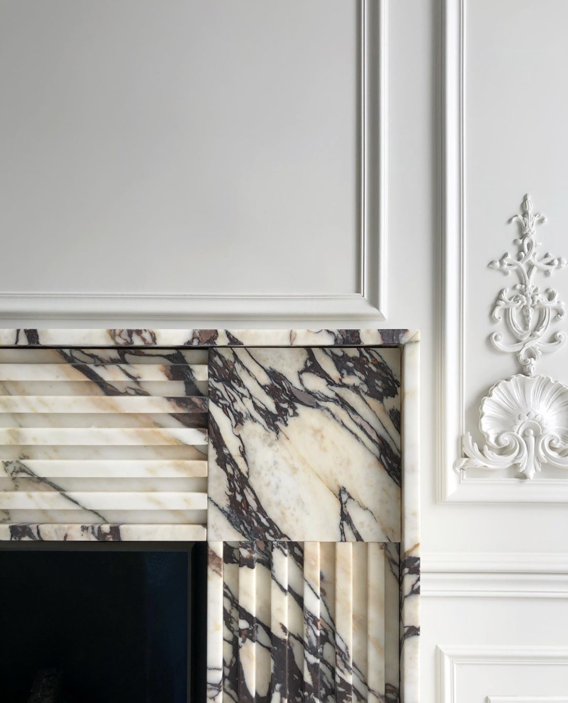 Detail of Tivoli luxury marble fireplace with dramatic natural veining and carved stone design
