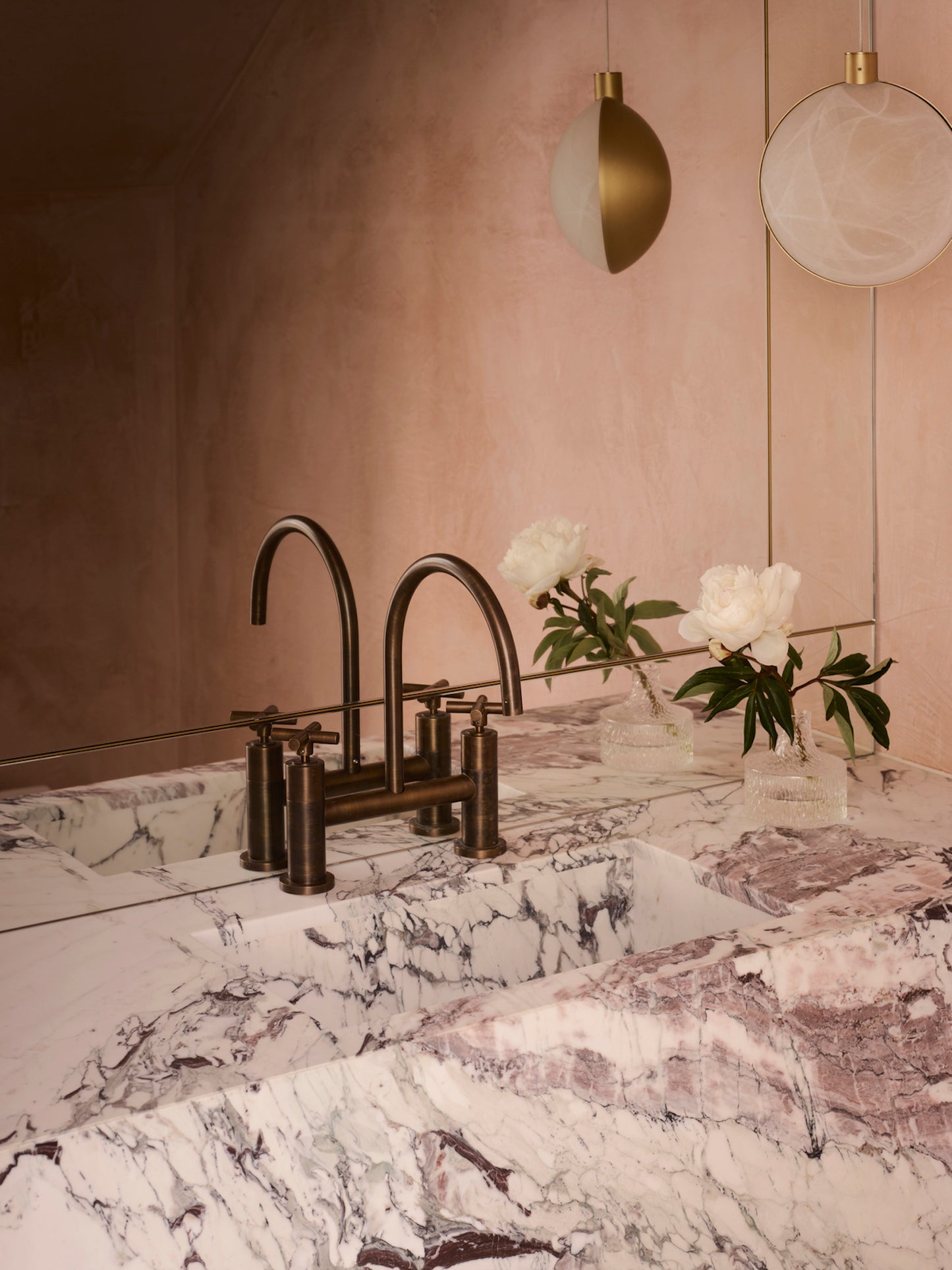 Toscana marble sink with integrated basin and double faucet in warm luxury bathroom interior