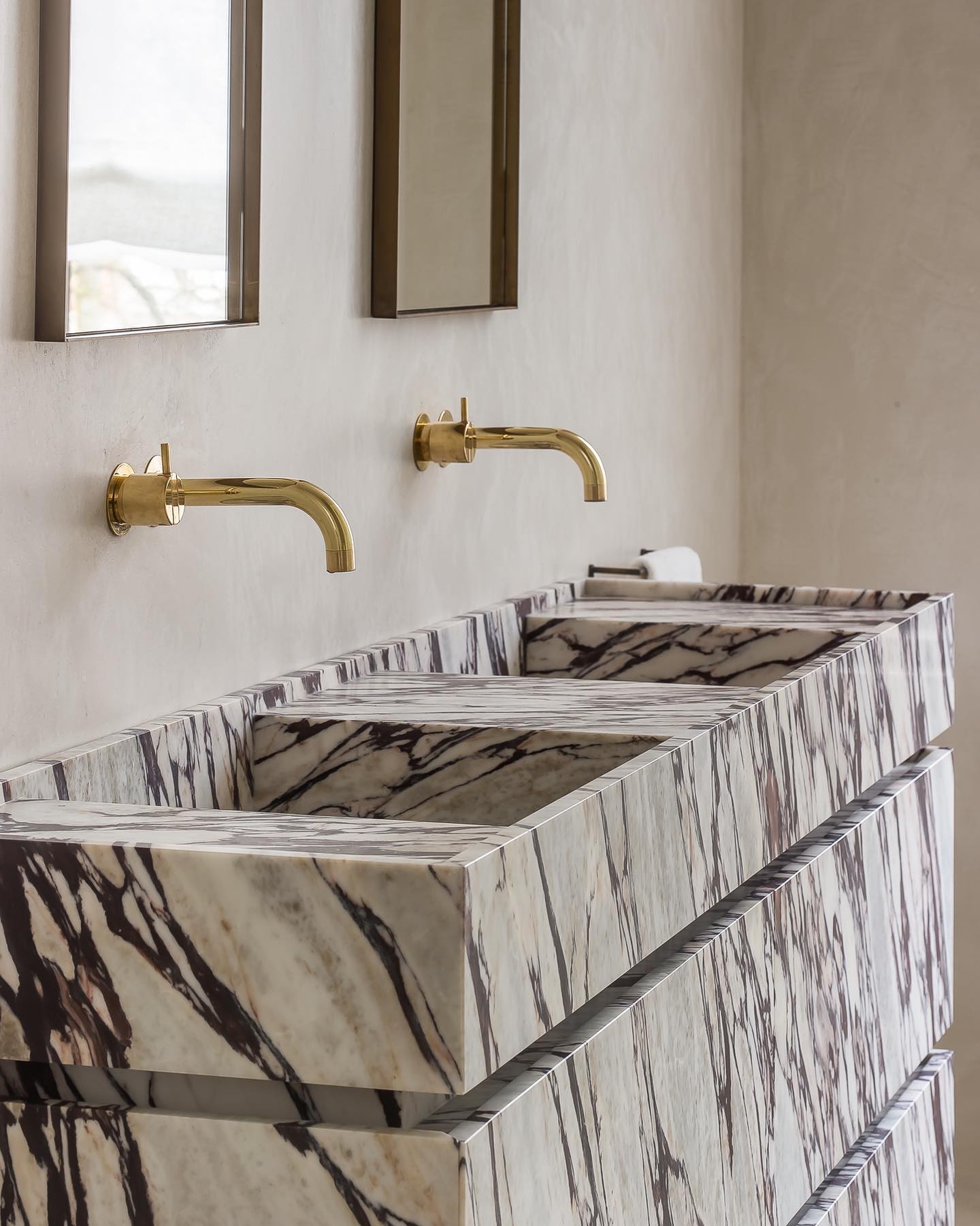 Venice double marble vanity with integrated basins and brass wall-mounted faucets in a luxury bathroom interior