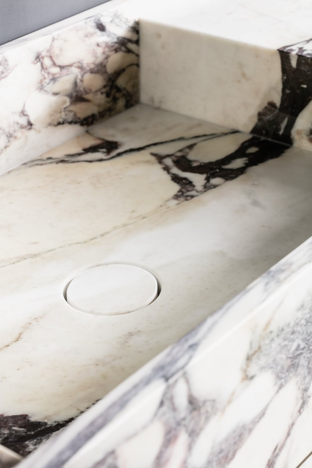 Close up of Venice marble vanity in Calacatta Viola showing integrated basin and natural stone veining detail