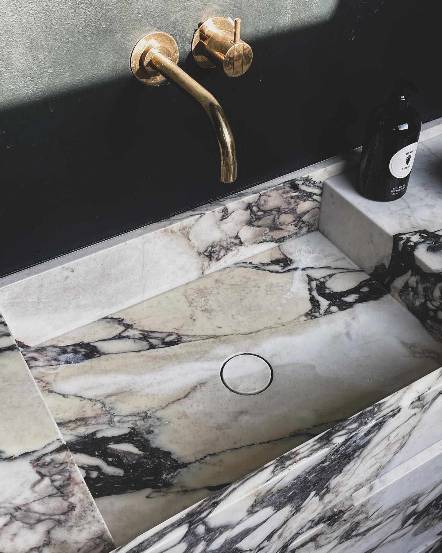 Venice marble vanity in Calacatta Viola with integrated sink in use showing water and natural stone surface