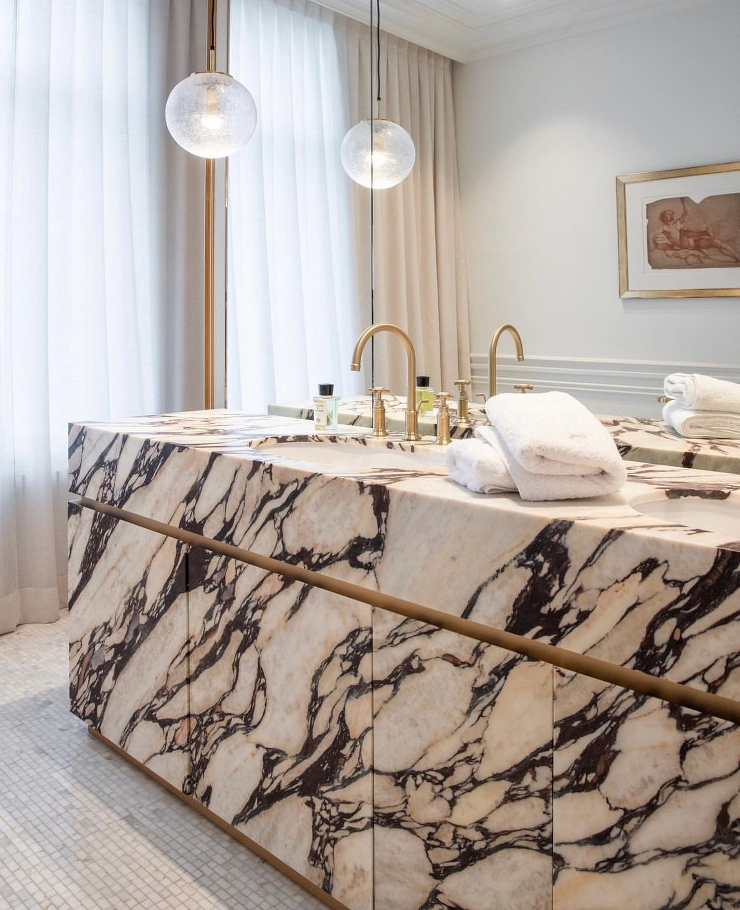 Luxury double marble vanity with integrated sinks, brass faucets and soft lighting in elegant bathroom