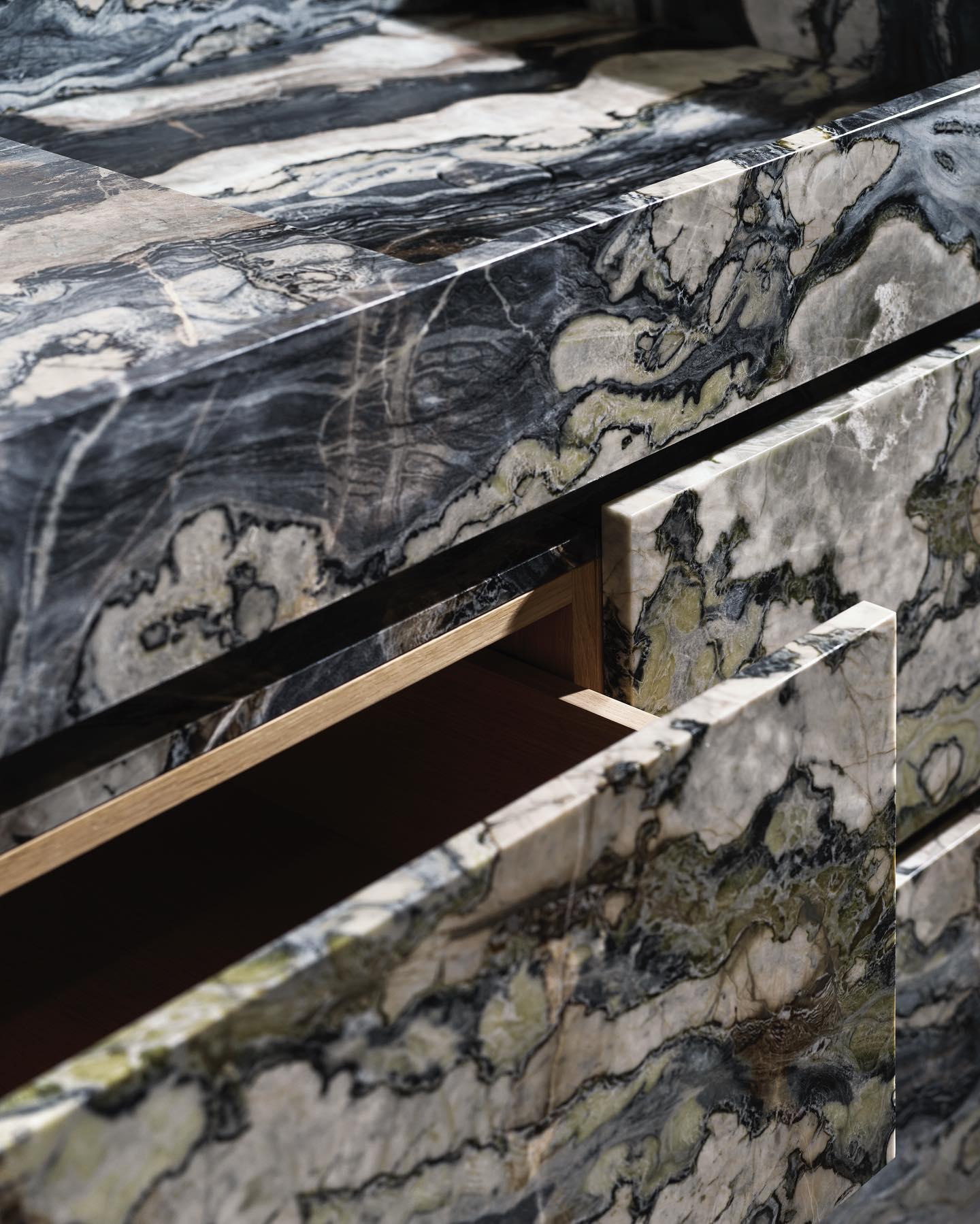 Close-up of handcrafted marble vanity drawer with natural stone veining and wooden interior detail