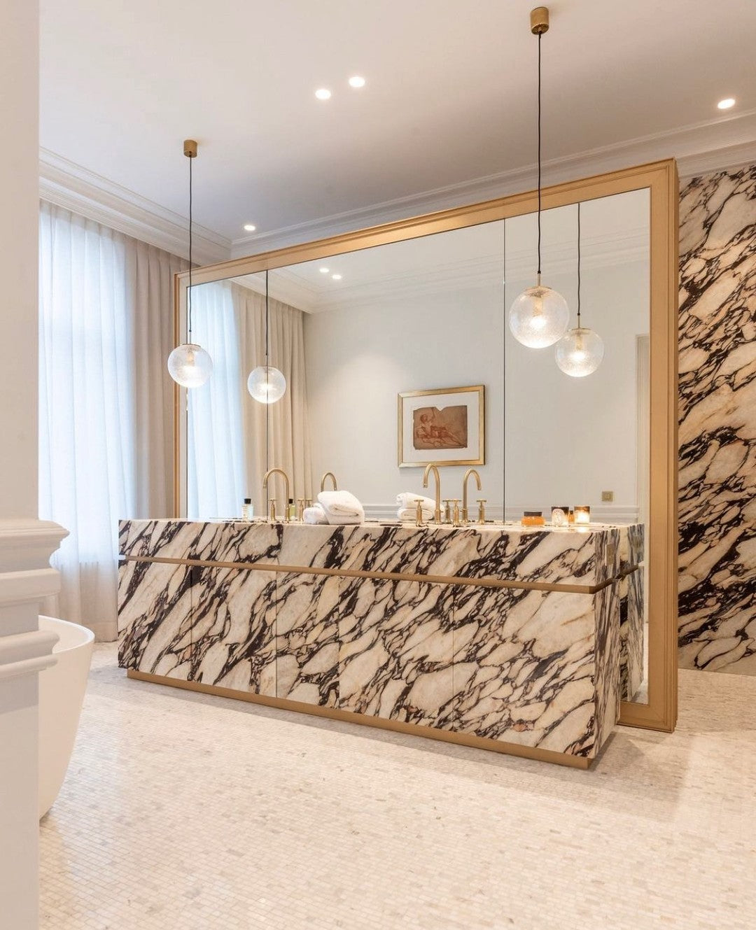 Luxury bathroom interior featuring Venice marble vanity with bold veining, brass faucets and full mirror wall