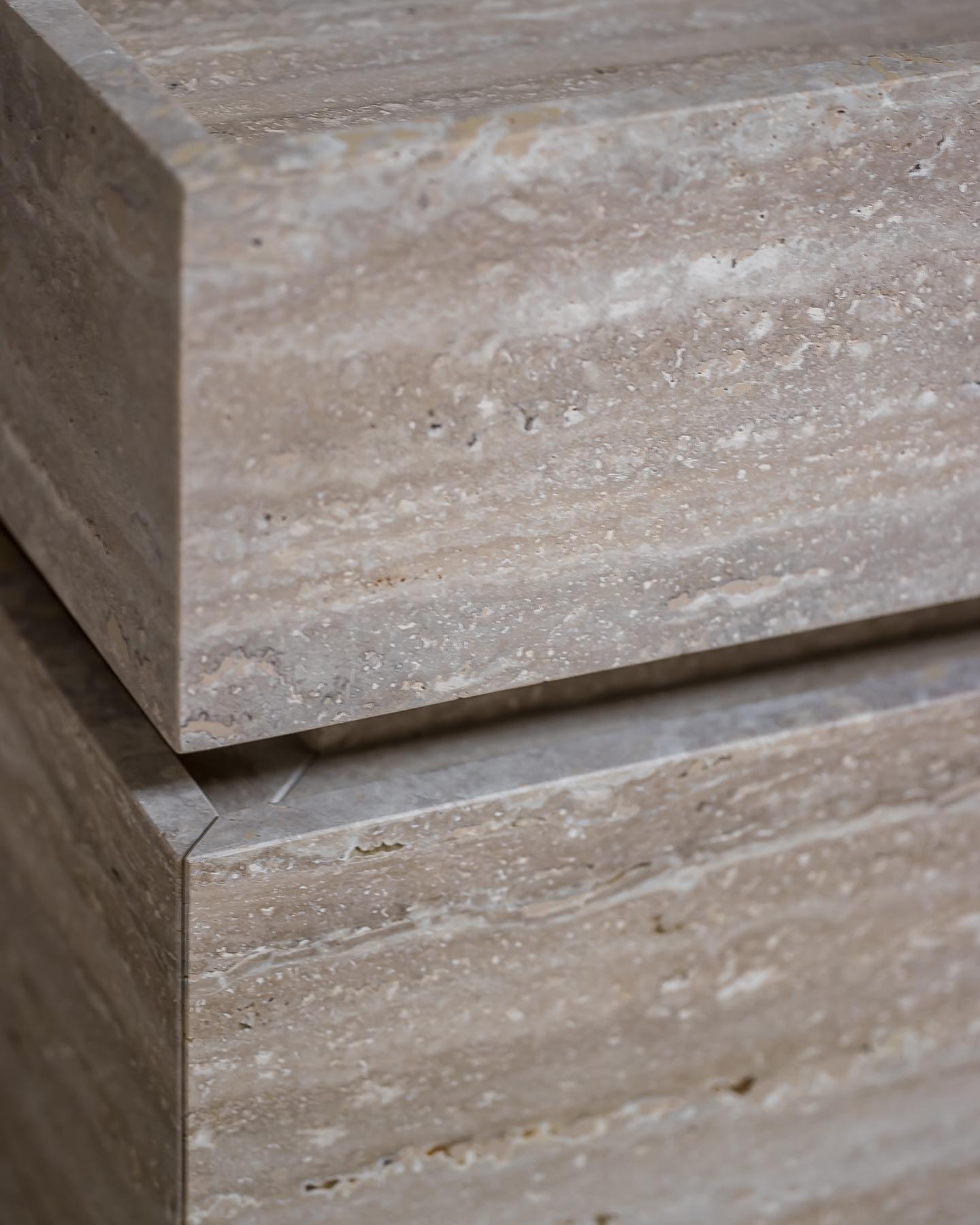 Close-up of Venice travertine vanity showing precise stone joinery and seamless corner detailing in natural stone