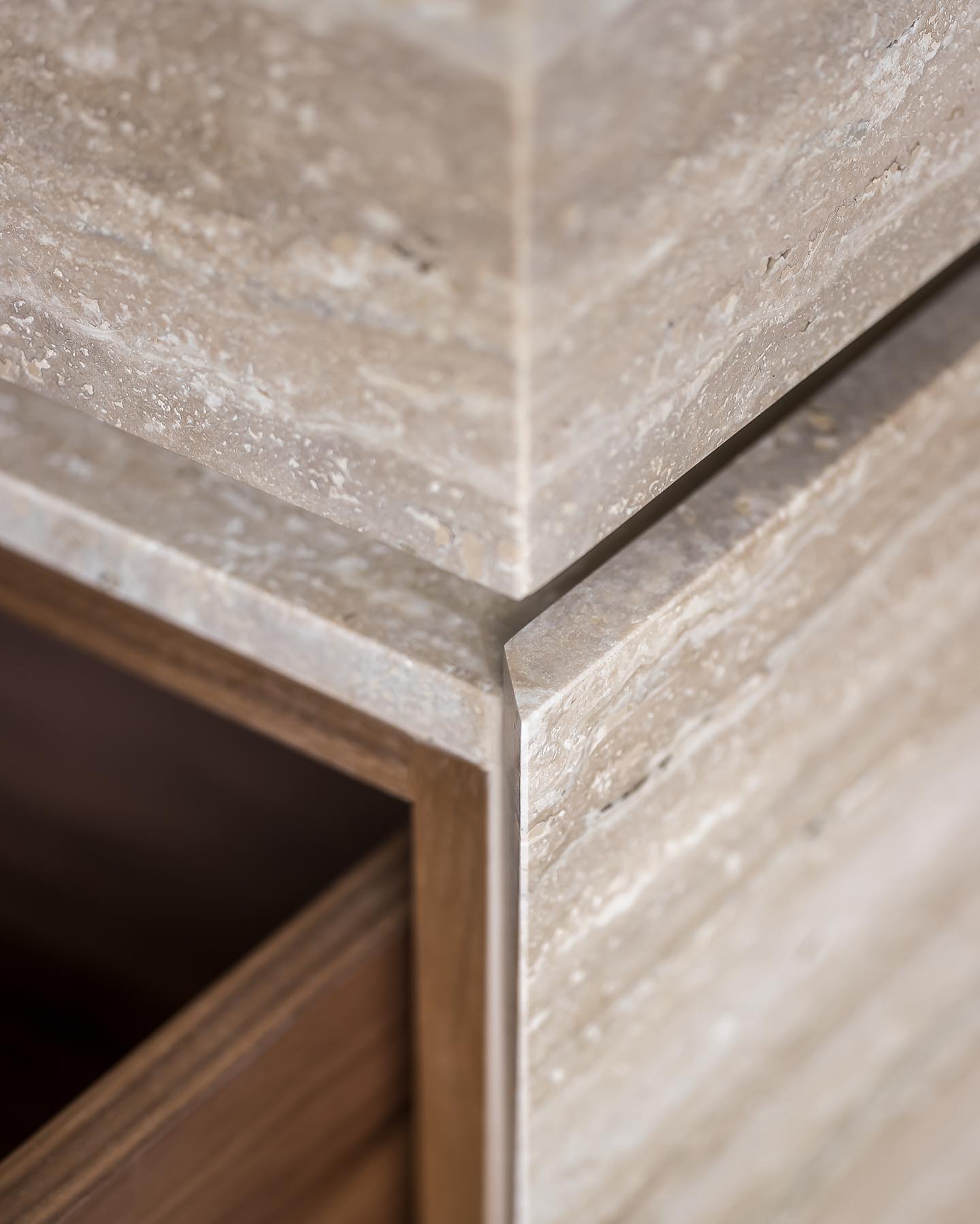 Close-up of Venice travertine vanity showing seamless stone edges and integrated wood drawer interior craftsmanship